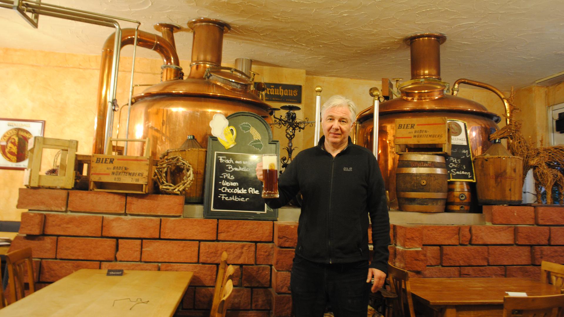 Christian Hochhaus steht mit einem Bier in der Hand vor den Bierfässern in seinem Brauhaus 