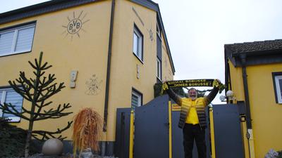 Dietmar Kreuser steht in BVB-Kleidung vor seinem Haus 