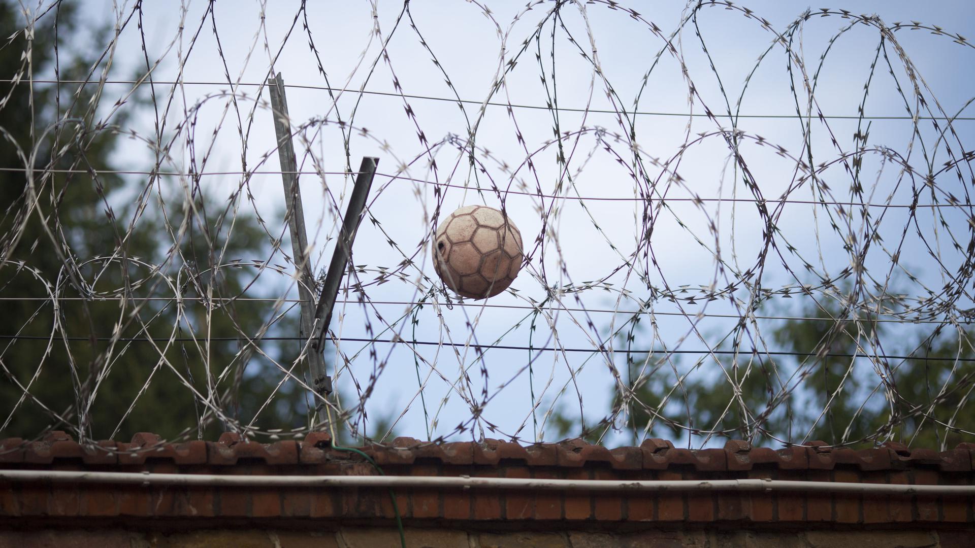 Ein Fußball hängt in der Justizvollzugsanstalt (JVA) im hessischen Butzbach im Stacheldraht auf der Gefängnismauer fest (Aufnahme vom 02.08.2012).  ++ +++ dpa-Bildfunk +++