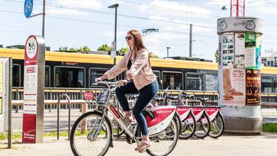 Eine Frau radelt mit einem KVV Next Bike vor einer Straßenbahn