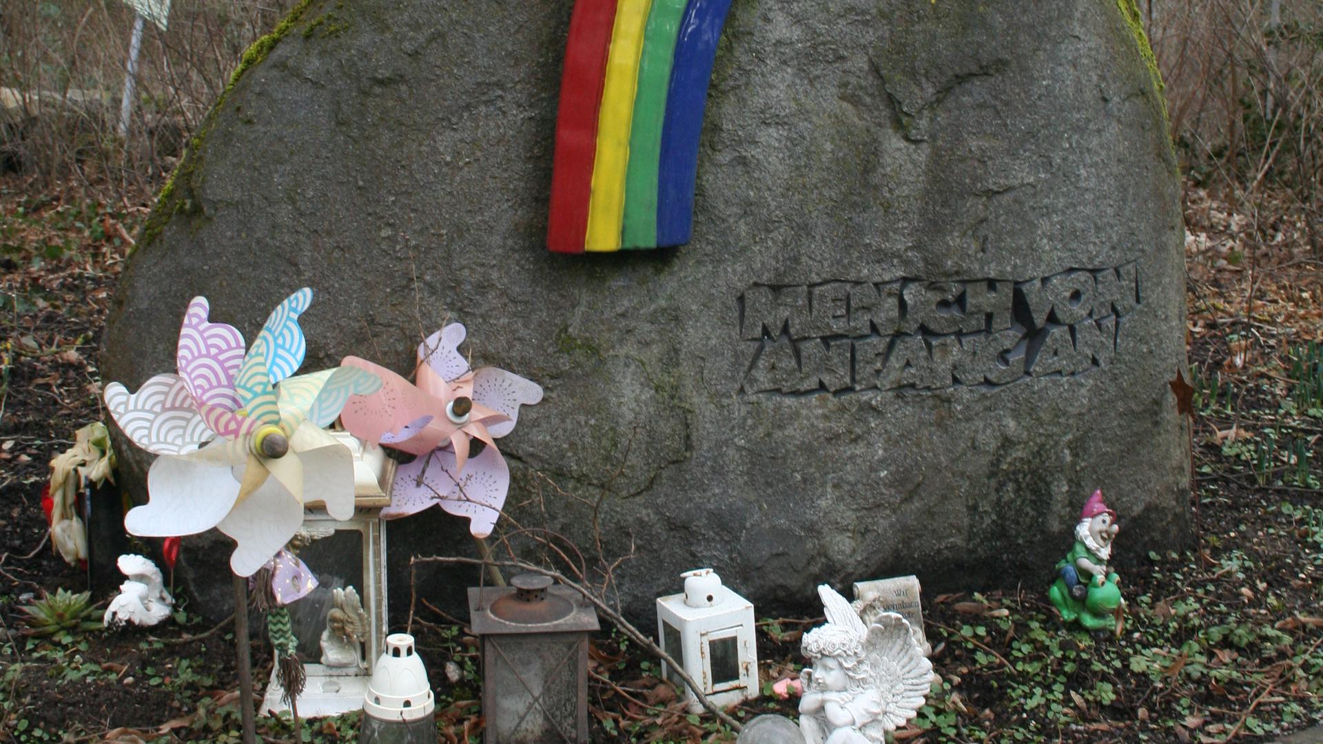 Naturstein mit Inschrift „Mensch von Anfang an“ mit Regenbogen