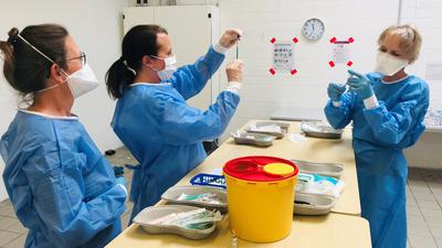 Drei Apothekerinnen füllen im Kreisimpfzentrum in Heidelsheim Corona-Impfstoff von Biontech ab.