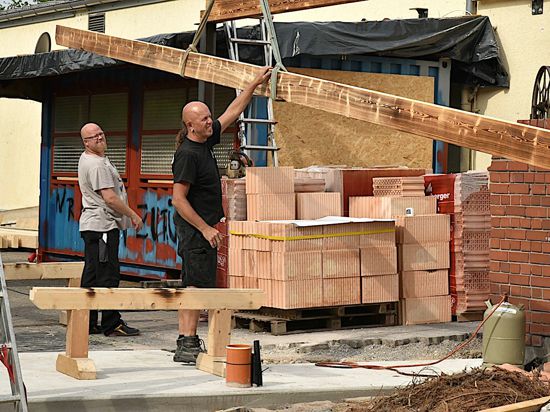 Zwei Helfer beteiligen sich am Umbau der Fabrik in Bruchsal. Ein langes Stück Holz wird gehalten.