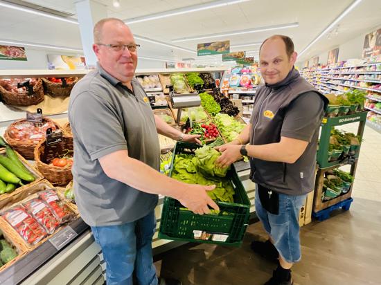 zwei Männer mit Warenkisten in einem Supermarkt 
