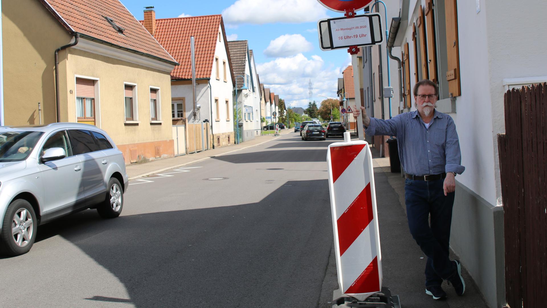Peter Kunz zeigt eine Engstelle an der Neutharder Hauptstraße, wo Rollstuhlfahrer oder Personen mit einem Kinderwagen auf die Straße ausweichen müssen.