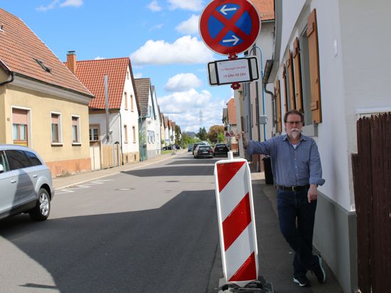 Peter Kunz zeigt eine Engstelle an der Neutharder Hauptstraße, wo Rollstuhlfahrer oder Personen mit einem Kinderwagen auf die Straße ausweichen müssen.