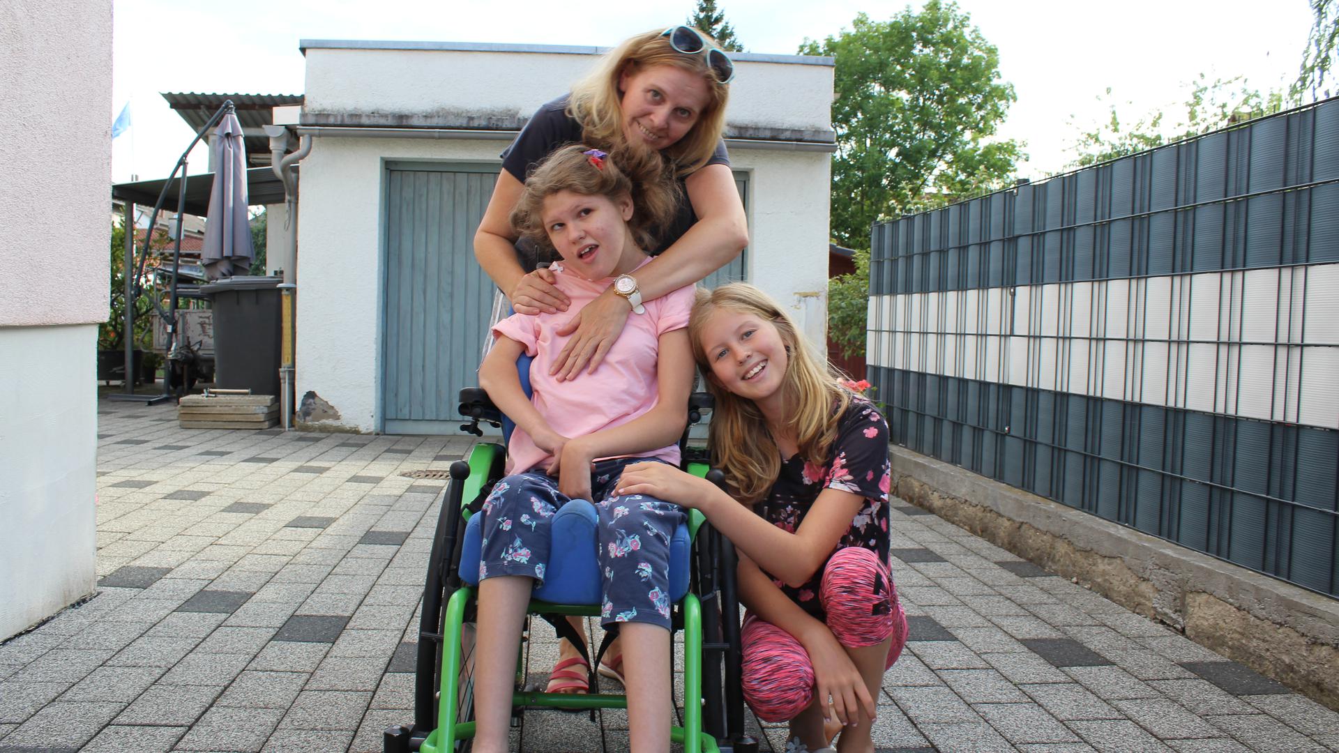 Mädchen im Rollstuhl zusammen mit Mutter und Schwester
