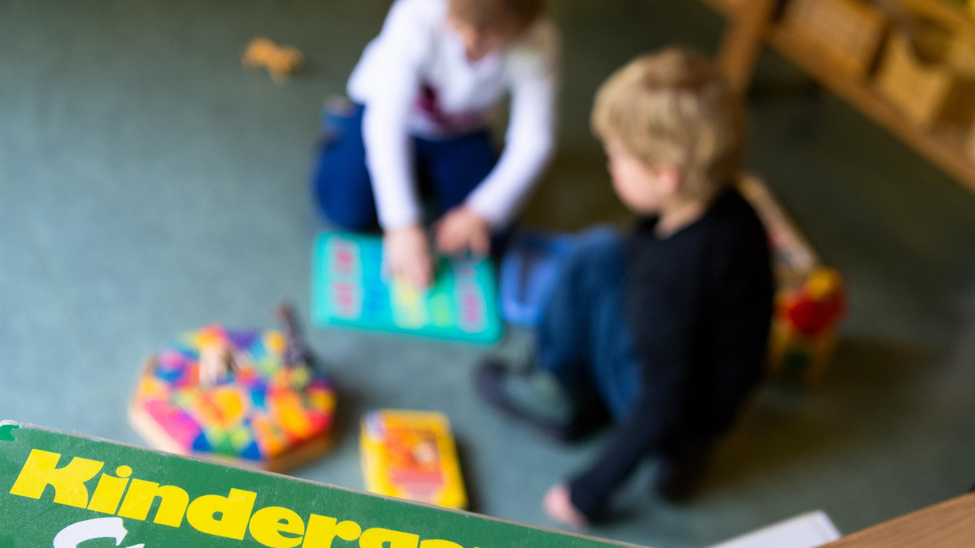 Ein Junge und ein Mädchen spielen in einem Kindergarten auf dem Boden. 