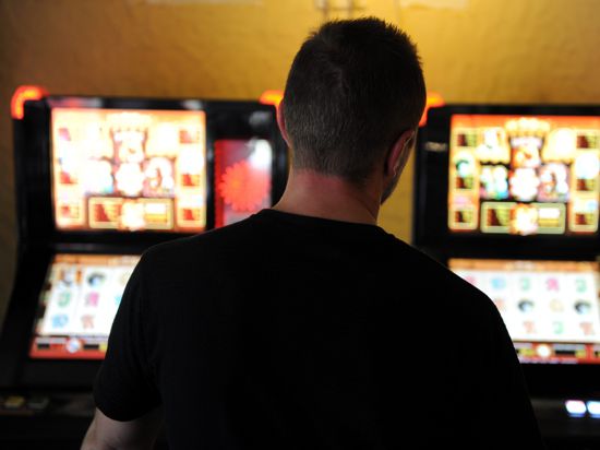 Ein Mann steht vor zwei Glücksspielautomaten