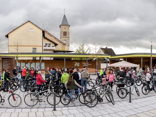 An blauen Bodenmarkierungen nehmen die Radfahrerinnen und Radfahrer Aufstellung für den Weltrekordversuch. Sie führen auch am neuen Fahhrad-Drehkreuz am neu gestalteten Kronauer Rathausplatz vorbei.