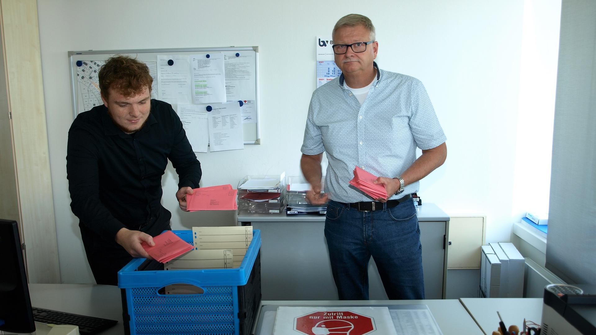 Amtsleiter Mario Berny und Mitarbeiter Lukas Störk sortieren in Philippsburg die eingegangenen Wahlbriefe.