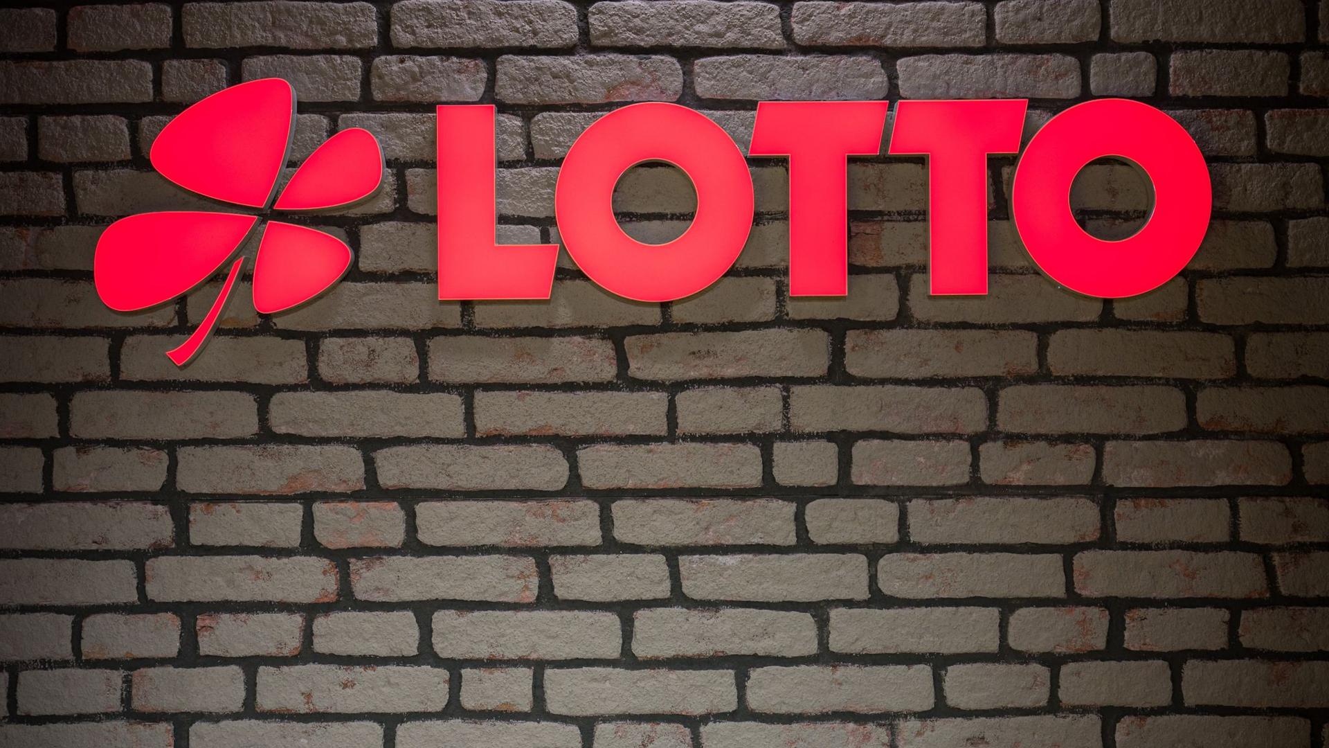 Das Lotto Logo leuchtet an einer Wand.