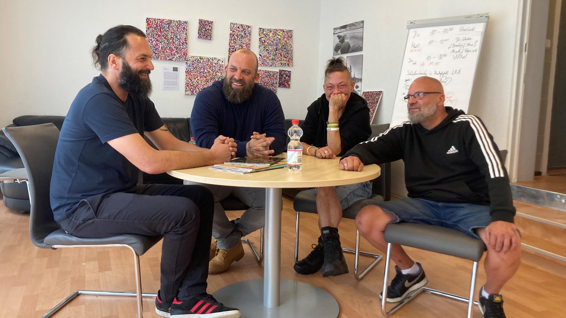 Die Streetworker Jochen Sawilla und Daniel Koch sitzen mit Bine und Sven an einem Tisch im Kontaktladen.