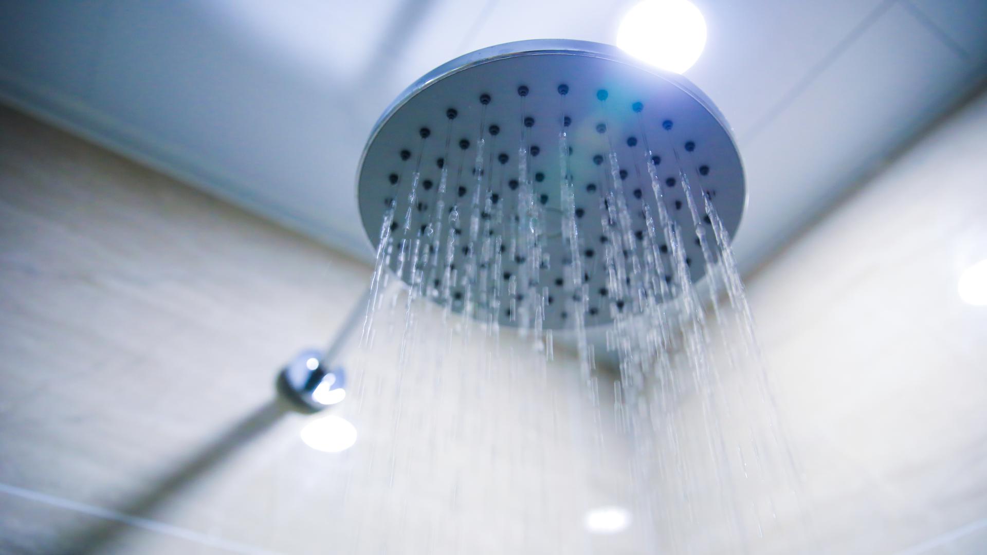 Aus einem Duschkopf läuft Wasser.
