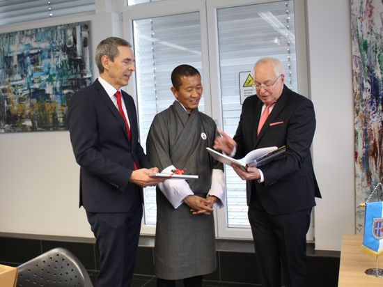 Michael Koch (links) und Bürgermeister Tony Löffler (rechts) zeigen dem Premierminister von Bhutan (Mitte) Fotoeindrücke von Ubstadt-Weiher