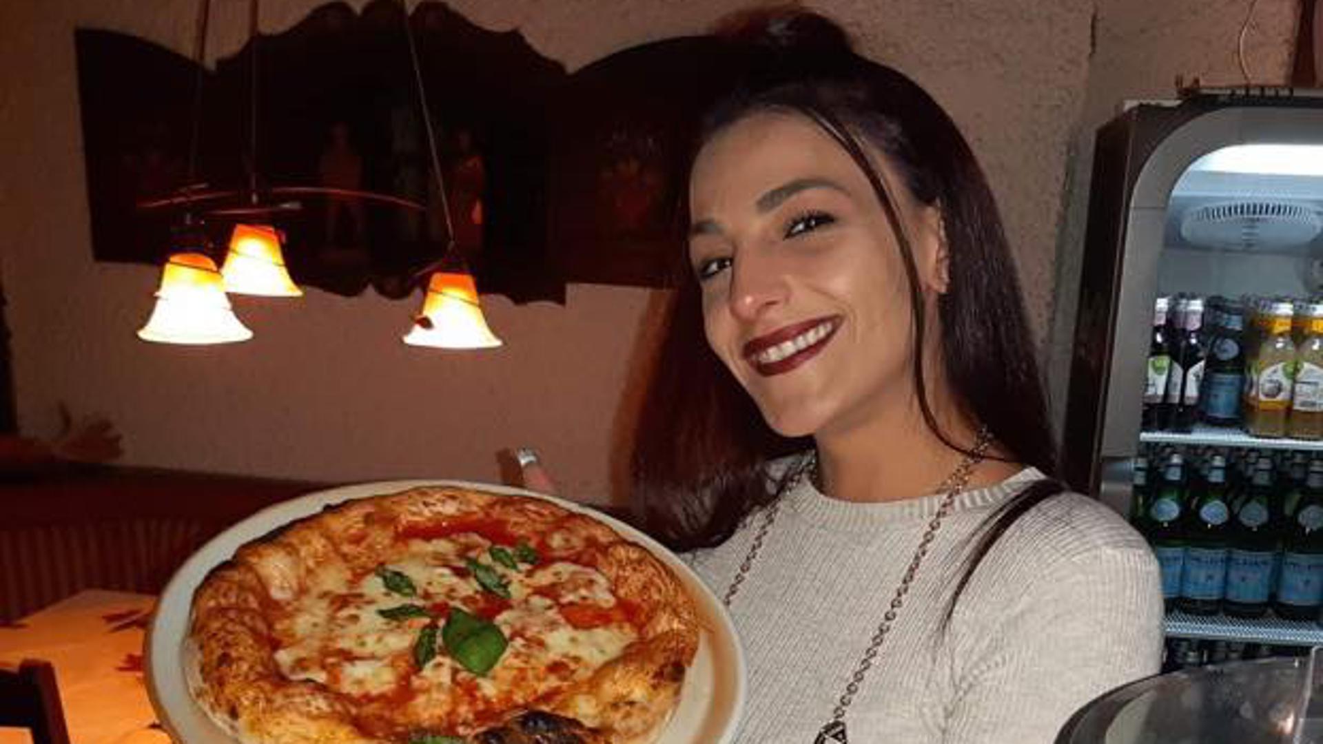 Junge Dame mit toller Pizza auf einem Teller in der Hand