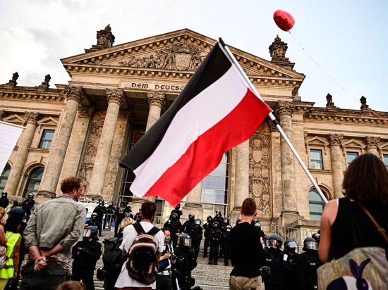 Teilnehmer einer Kundgebung gegen die Corona-Maßnahmen stehen Ende August vor dem Reichstag, eine Teilnehmerin hält eine Reichsflagge.