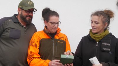 Zwei Frauen und ein Mann blicken auf ein Gerät zur Lautbestimmung der Fledermäuse