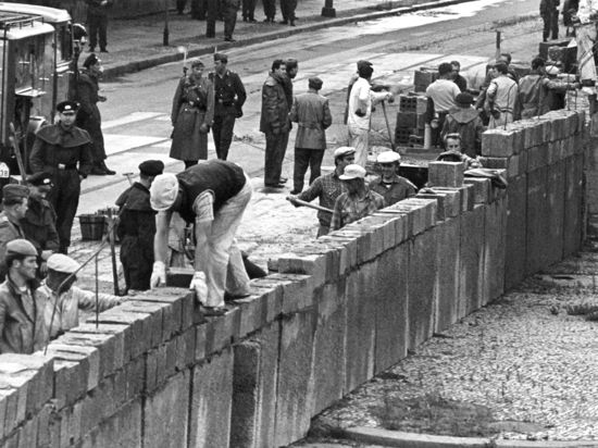 Unter der Aufsicht von bewaffneten Volkspolizisten errichtet eine Ostberliner Maurerkolonne am an der sowjetisch-amerikanischen Sektorengenze am Potsdamer Platz eine Mauer.