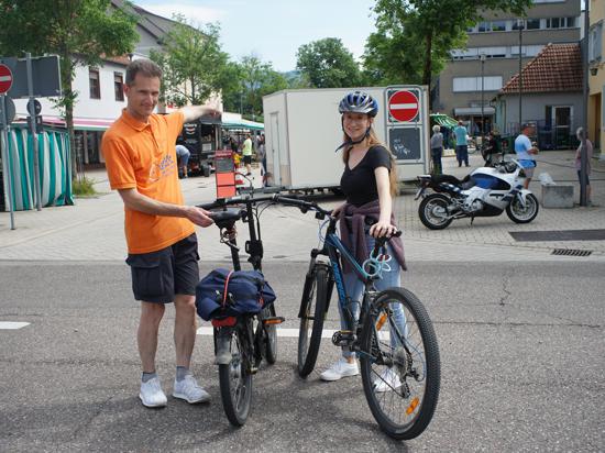 Ein Mann und ein Mädchen stehen mit ihrem Fahrrad auf einer Kreuzung.