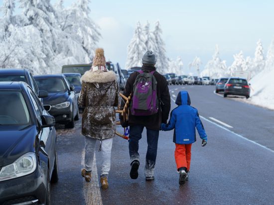 Eine Familie läuft zu ihrem Auto das an der Schwarzwaldhochstrasse geparkt ist. 