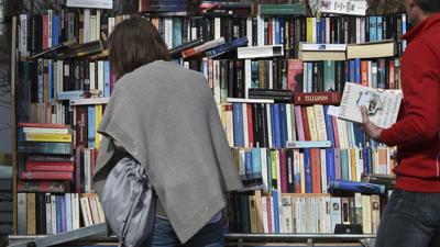 Eine Frau stöbert beim Flohmarkt zwischen Büchern.