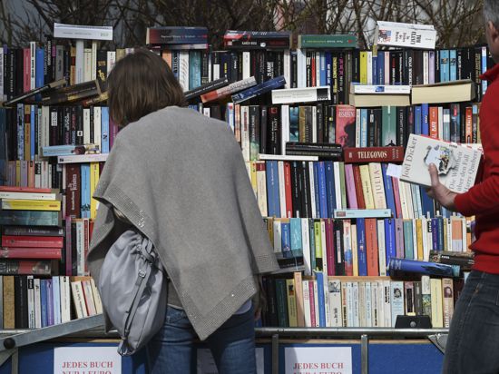Eine Frau stöbert beim Flohmarkt zwischen Büchern.