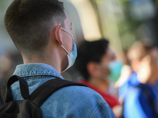 Schüler  tragen Mundschutz, während sie vor Unterrichtsbeginn in die Hygieneregeln eingewiesen werden. 