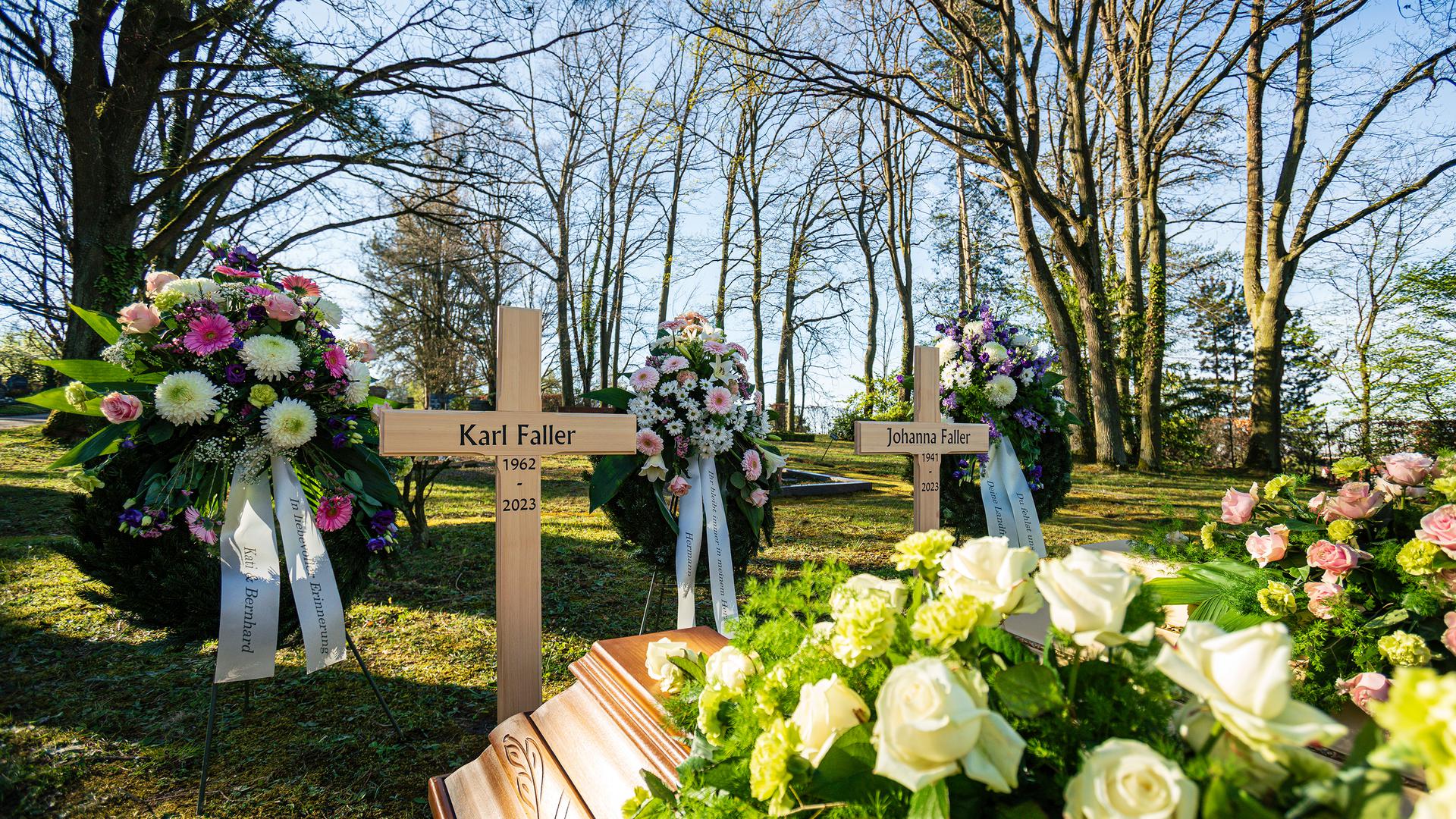Holzkreuze und Blumenkränze auf einem Friedhof