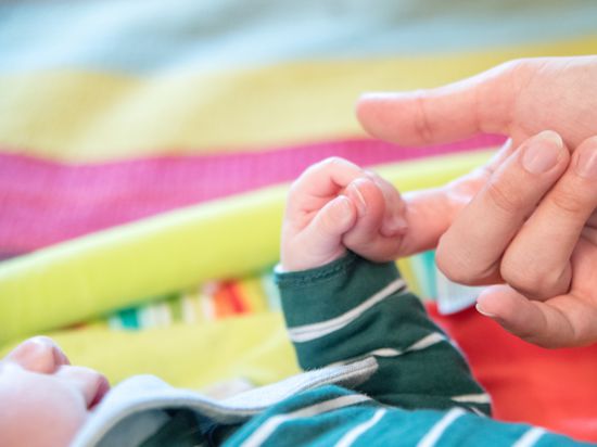Baby hält Finger eines Erwachsenen