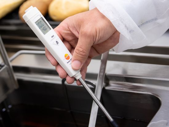 Hygiene im Blick: Ein Lebensmittelkontrolleur überprüft die Temperatur einer Friteuse in einem Restaurant.  