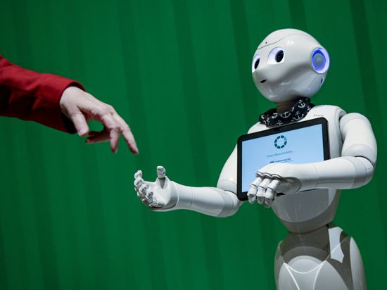 Ein Roboter interagiert mit einer Frau auf einer Veranstaltung, die eine Auswahl hoch entwickelter Roboter aus verschiedenen Bereichen zeigt, die einen Einblick in die aktuellen Möglichkeiten der Künstlichen Intelligenz gibt.