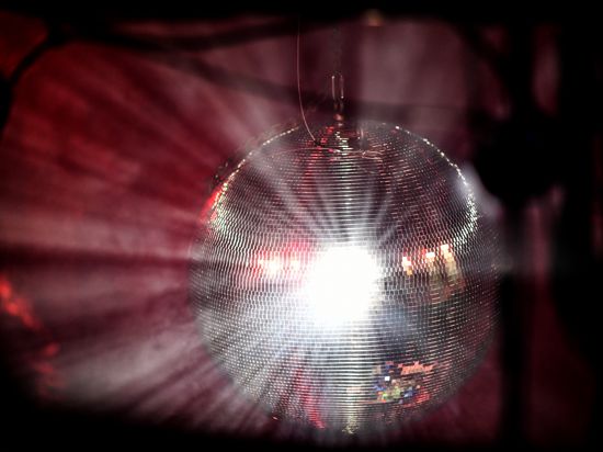 Eine Diskokugel dreht sich  und reflektiert das einfallende Licht der Scheinwerfer und Lampen.