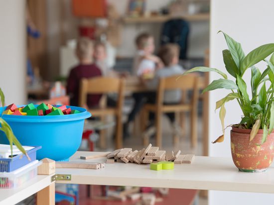 Kinder sitzen im Rahmen der Notbetreuung in einem Kindergarten während des Mittagessens an einem Tisch und sind in einem Spiegel zu sehen.
