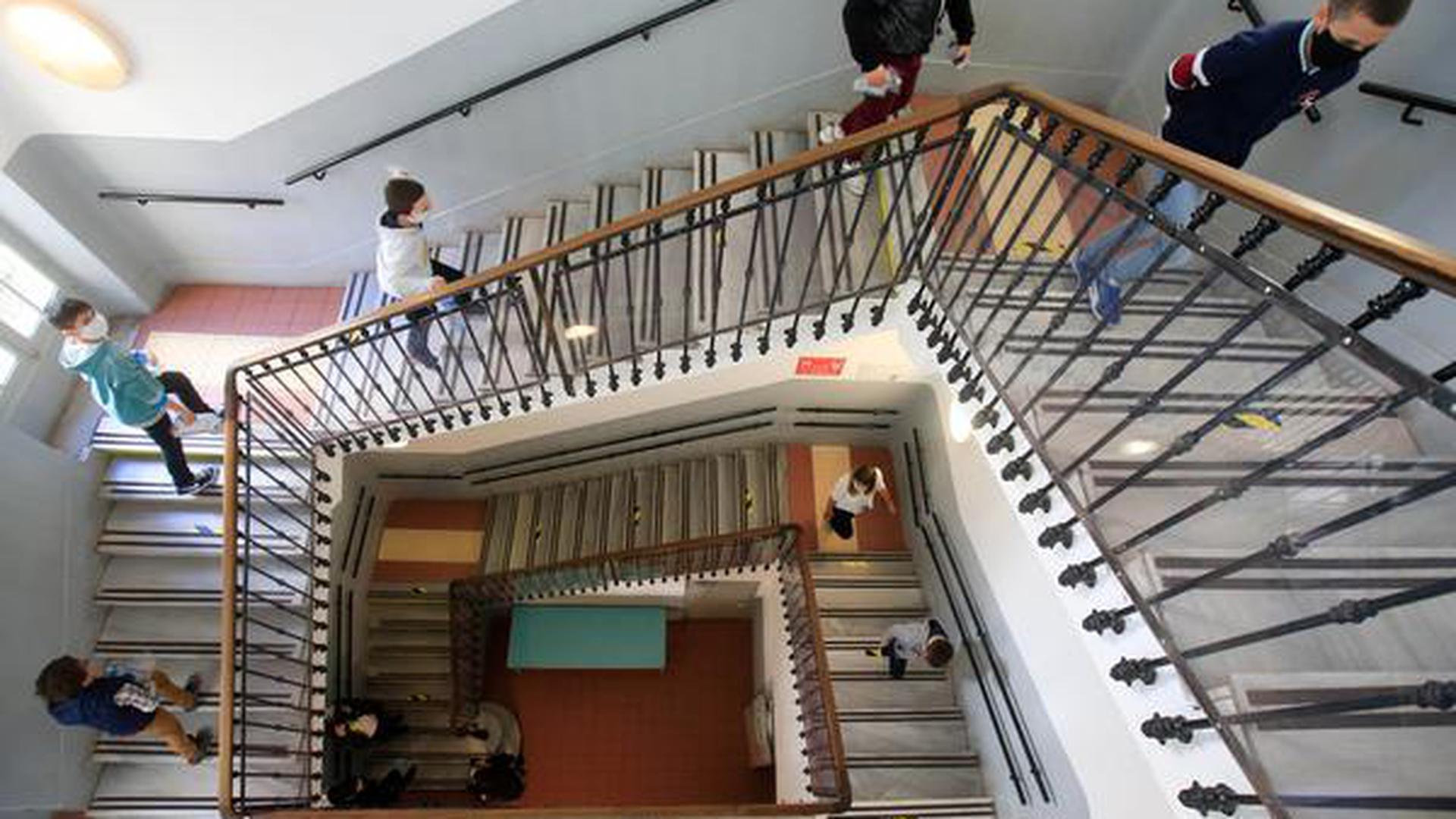 Schulkinder mit Gesichtsmasken gehen unter Beachtung der Abstandsregelungen eine Treppe in der wiedereröffneten Simone Veil Grundschule hoch.