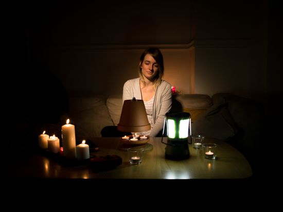 Eine Frau sitzt in einem lediglich mit Kerzen beleuchteten Raum.