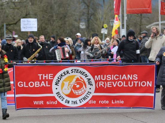 Zwei Frauen bei einer Demo halten ein Banner mit der Aufschrift „The Musicians Global (R)Evolution“
