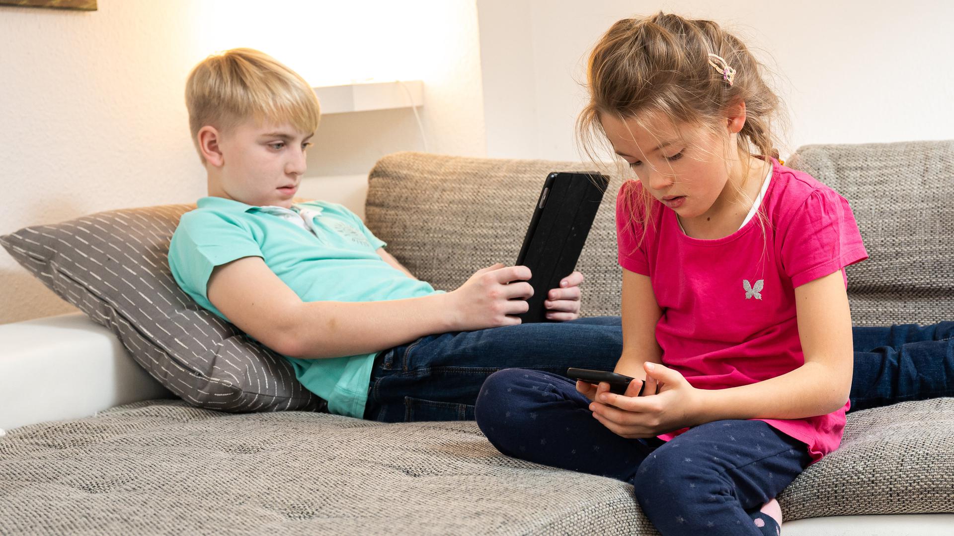 Children with mobile devices on a sofa