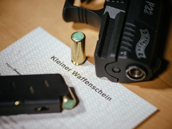 Eine Waffe und Munition liegen auf einem kleinen Waffenschein. 