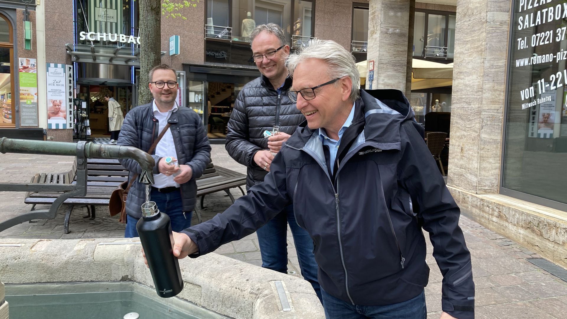 Bürgermeister Alexander Uhlig befüllt an einem Brunnen seine Trinkflasche mit Wasser.