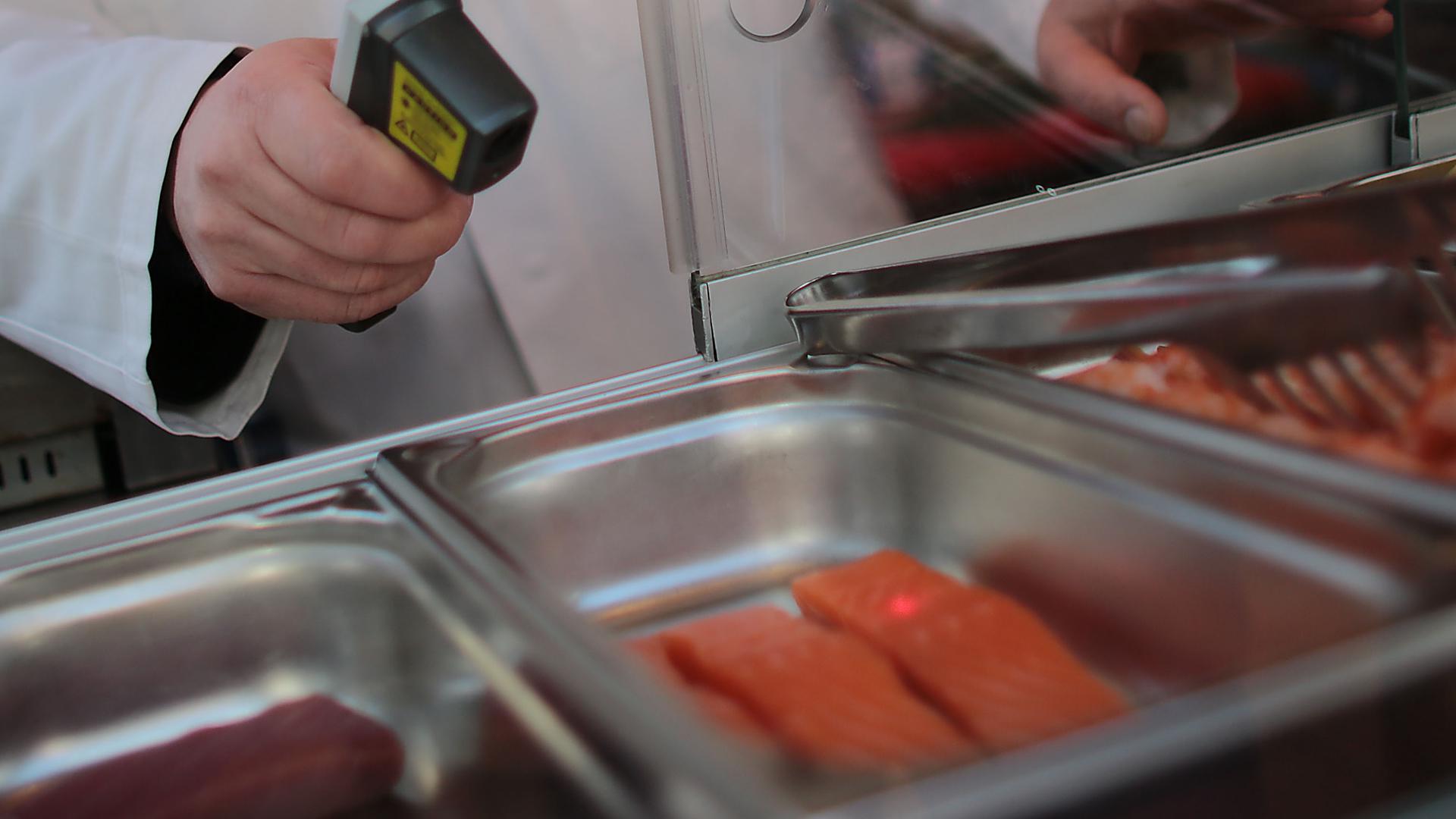Ein Lebensmittelkontrolleur misst auf dem Symbolbild die Temperatur von Lachs. 