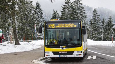 Ein Linienbus fährt durch eine verschneite Landschaft.