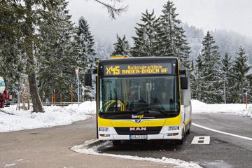 Ein Linienbus fährt durch eine verschneite Landschaft.