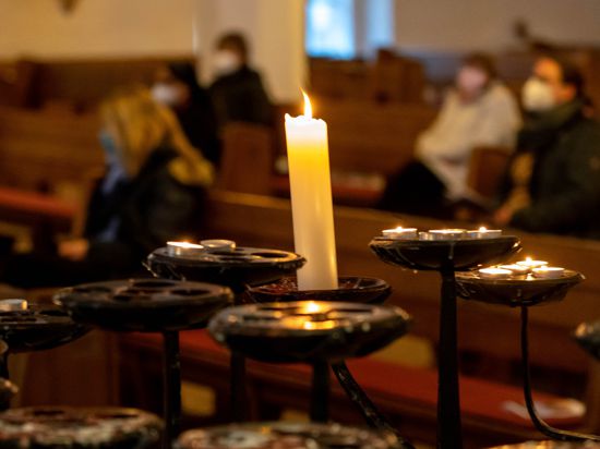 Gäste des ökumenischen Gedenkgottesdienstes für die Opfer und Leidtragenden der Corona-Pandemie sitzen in der St. Nikolai Kirche in den Bänken. 