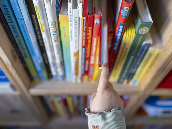Ein Kind zieht ein kinderbuch aus einem Bücherregal.