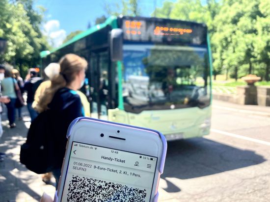 Ein Fahrgast zeigt an einer Bushaltestelle in Baden-Baden sein digitales 9-Euro-Ticket auf dem Handy.