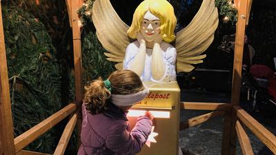 Ein Mädchen wirft seinen Wunschzettel in den  Himmelsbriefkasten auf dem Christkindelsmarkt in Baden-Baden.