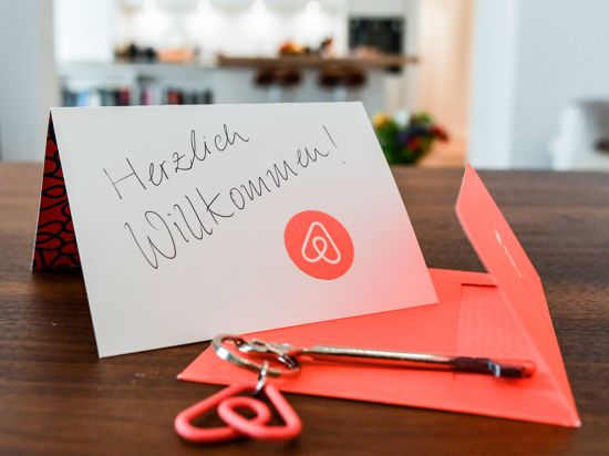 Ein Schlüssel mit einem Airbnb-Anhäger und eine Herzlich-Willkommen-Karte liegen in der Wohnung eines Airbnb-Gastgebers. 