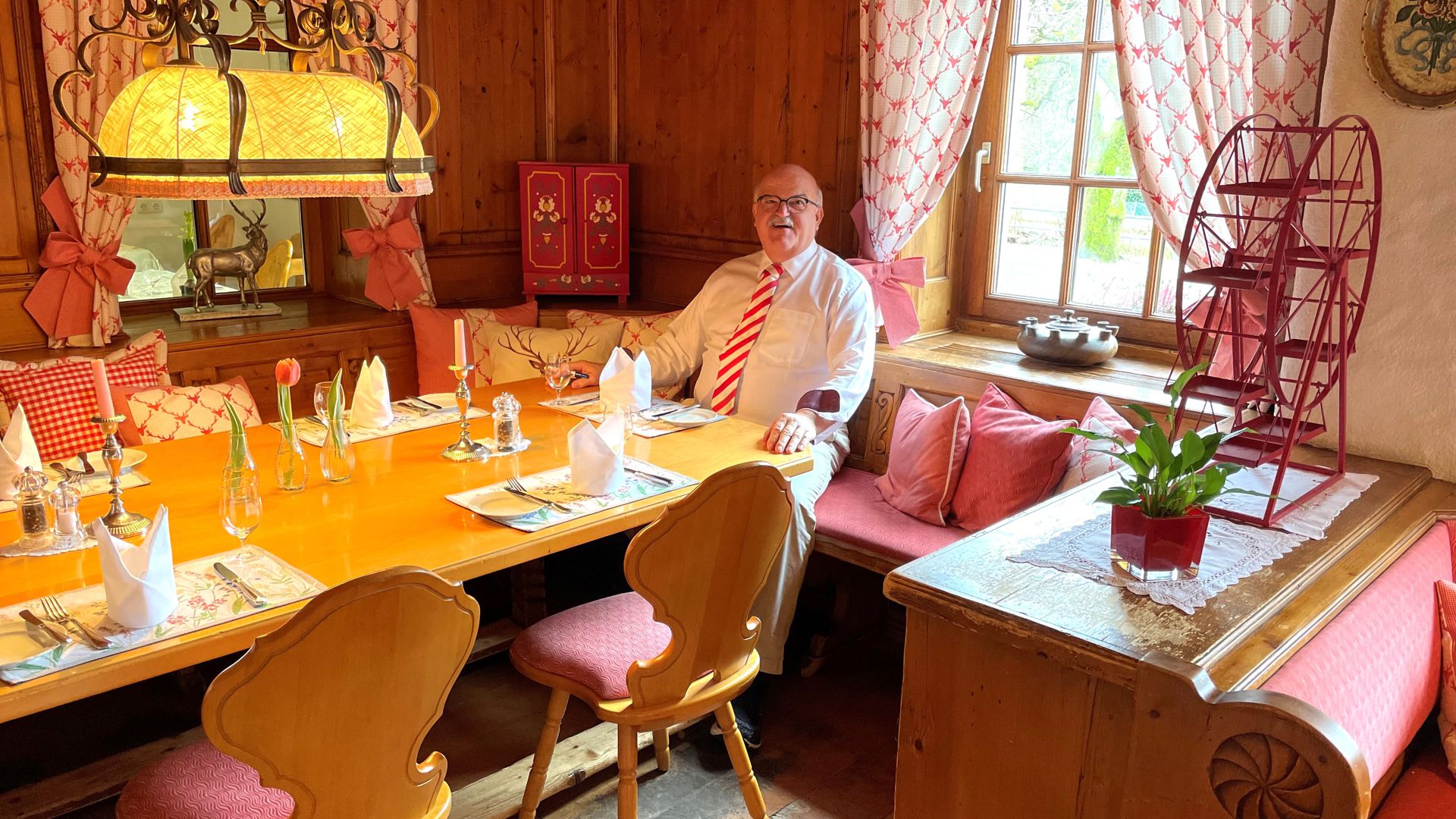Hans Schindler sitzt in seinem Restaurant an einem gedeckten Tisch. 