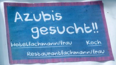 Ein selbstgemaltes „Azubis-Gesucht“-Schild hängt vor einem Hotel.